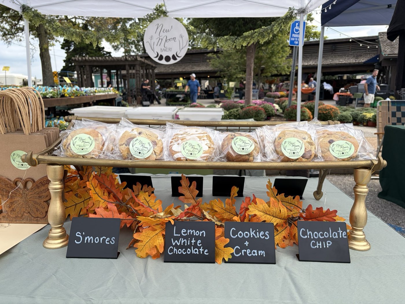 Individually wrapped New Moon cookies on a gold display rack with fall leaves and chalkboard name cards