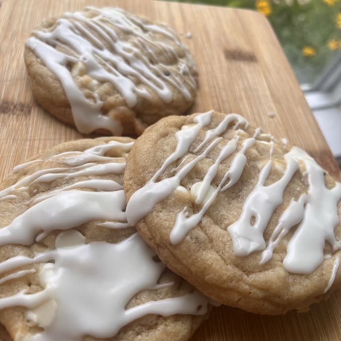 Lemon white chip cookies with a white drizzle on a wooden board